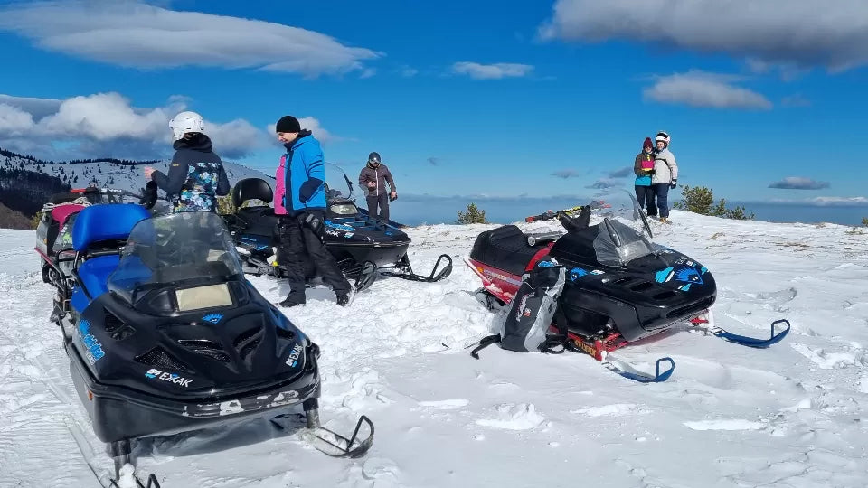 Snowmobile rider near Petrohan with views toward Mount Kom