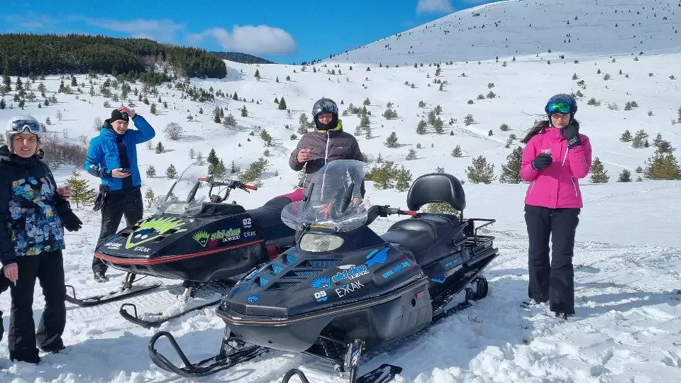 Two participants sharing one snowmobile on a snowy trail at Petrohan
