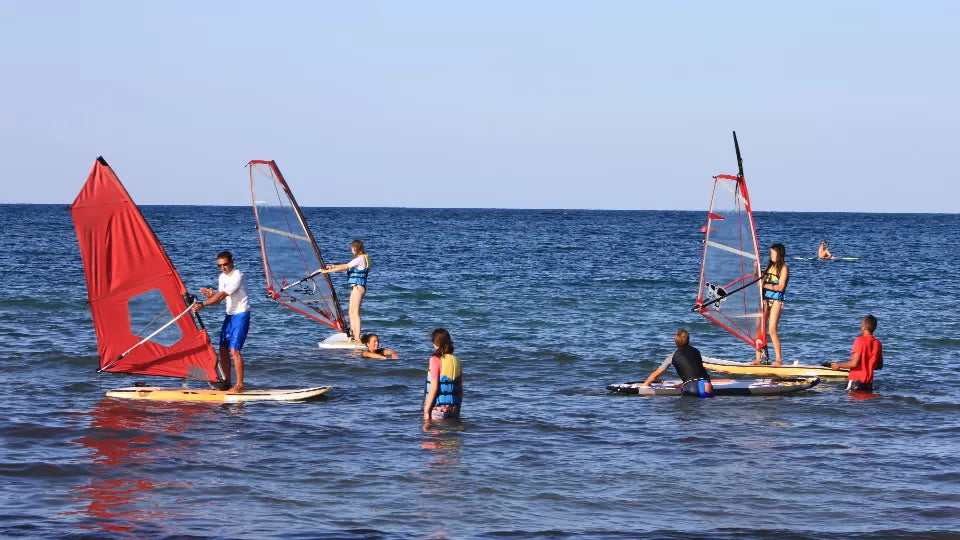 Child learning windsurfing with an instructor at Camping Nestinarka, Tsarevo