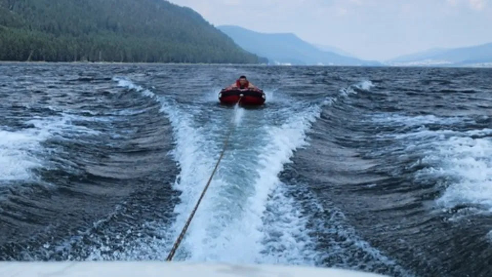 Inflatable tow‑tube ride behind a motorboat on Dospat Reservoir