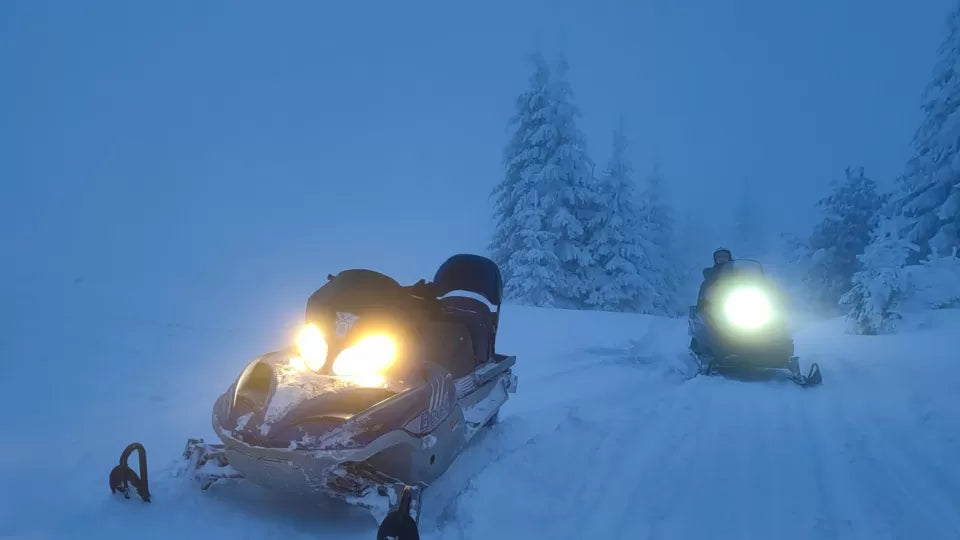 Night snowmobile tour in Petrohan with guide and riders on snow